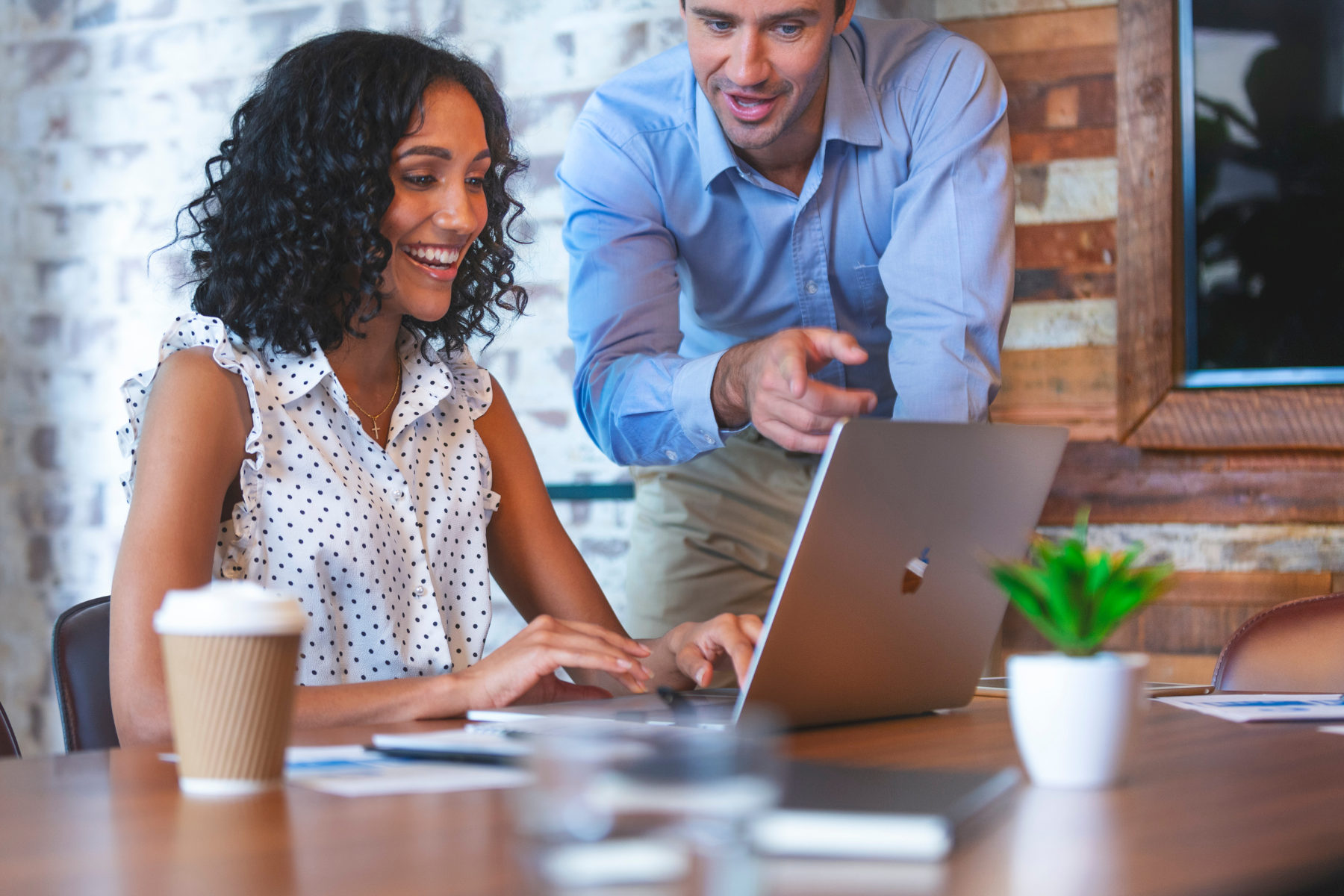 Two staff members gathered at a laptop smiling.